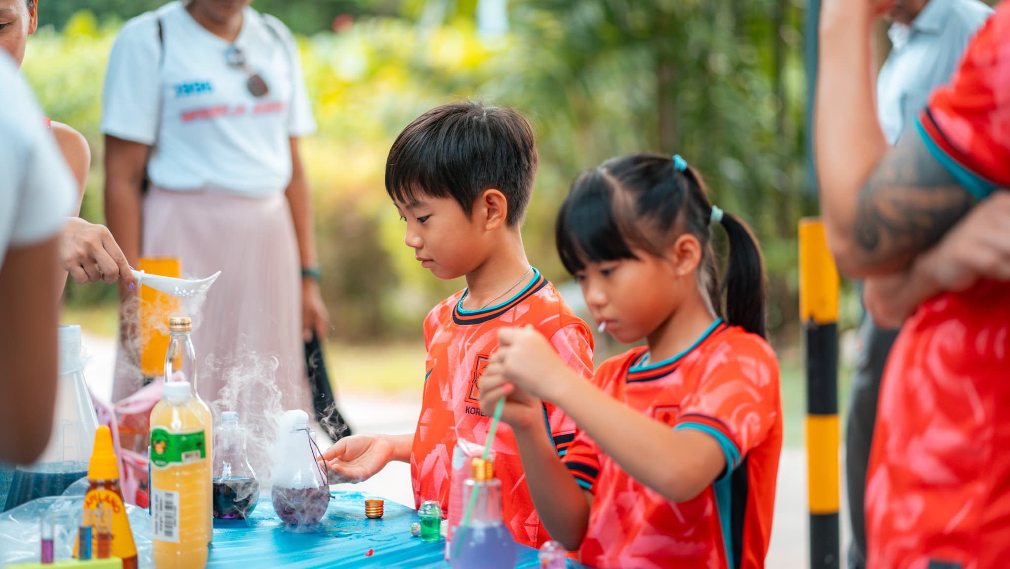 Kids mixing flasks at an outdoor science bench